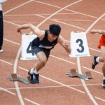 Young male sprinters launching off at the starting line, showcasing athletic determination on the track.