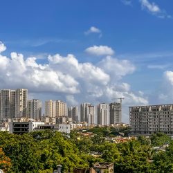 Stunning cityscape of Hyderabad's skyline with lush green foliage under a vibrant blue sky.